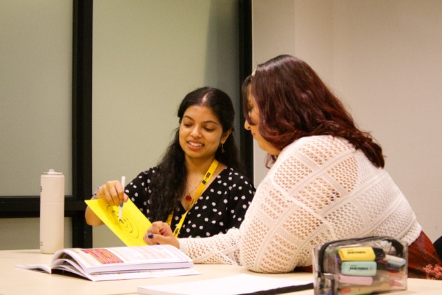 NSEMM tutor working one-on-one with a student at a desk, both looking at educational materials